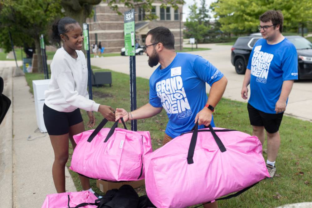 Volunteer carrying bright pink bag while shaking hands with new arrival